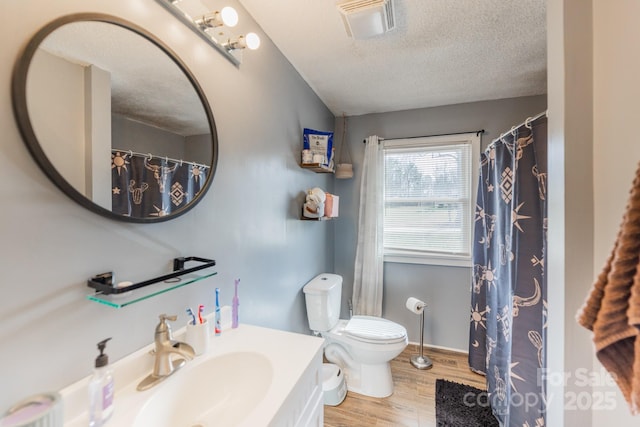 full bathroom featuring visible vents, toilet, a textured ceiling, wood finished floors, and vanity