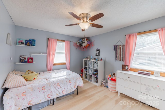 bedroom with a textured ceiling, a ceiling fan, and wood finished floors