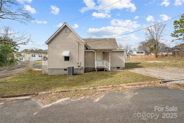 exterior space with a shingled roof, a lawn, central AC, and crawl space