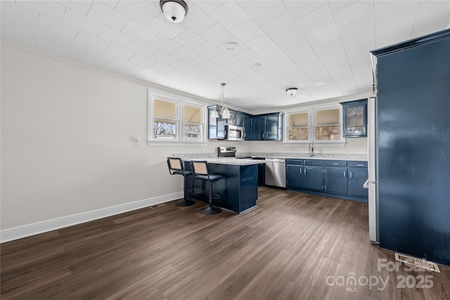 100 Lear St, Rockingham, NC 28379 - kitchen with blue cabinets, stainless steel appliances, a kitchen bar, a peninsula, and dark wood-type flooring