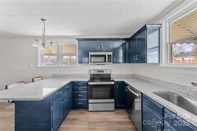 100 Lear St, Rockingham, NC 28379 - kitchen with stainless steel appliances, blue cabinetry, a peninsula, healthy amount of natural light, and crown molding
