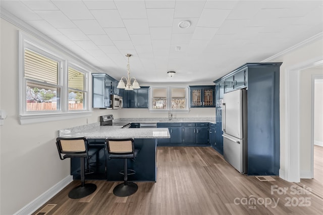 100 Lear St, Rockingham, NC 28379 - kitchen featuring stainless steel appliances, a peninsula, blue cabinets, healthy amount of natural light, and crown molding