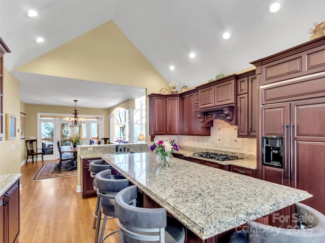 kitchen featuring paneled built in fridge, a center island, a kitchen bar, stainless steel gas cooktop, and pendant lighting