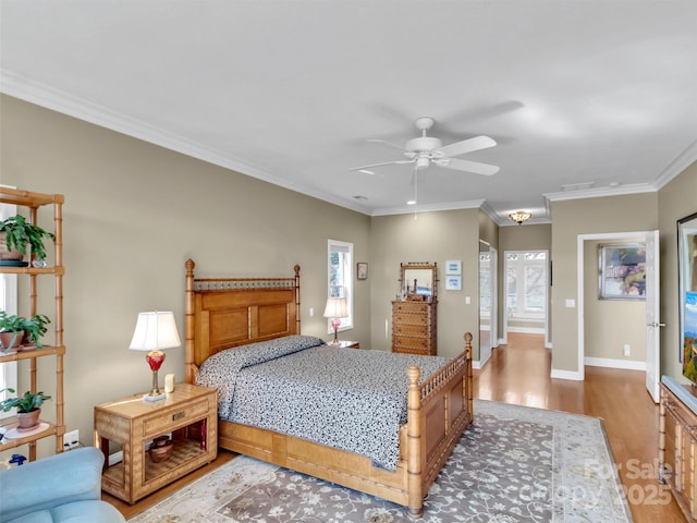 bedroom featuring visible vents, ornamental molding, a ceiling fan, wood finished floors, and baseboards