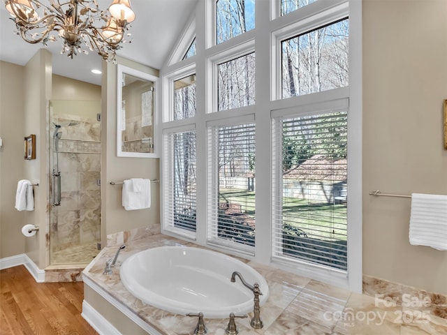 full bathroom with a stall shower, lofted ceiling, wood finished floors, an inviting chandelier, and a bath