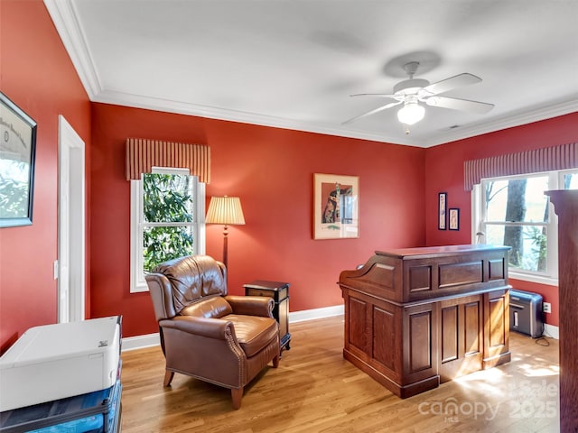 living area with ornamental molding, light wood finished floors, a ceiling fan, and baseboards