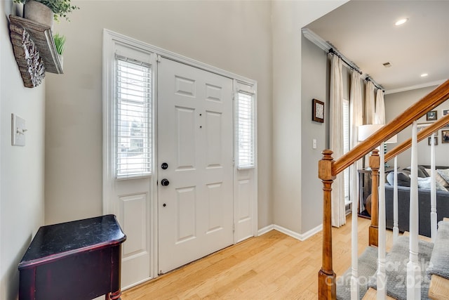 entrance foyer featuring hardwood / wood-style flooring, ornamental molding, and a wealth of natural light