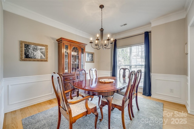 dining room with ornamental molding, a chandelier, and light hardwood / wood-style floors