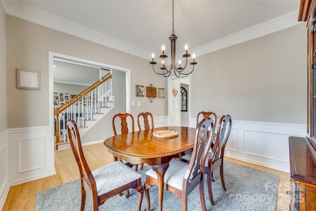 dining space with light hardwood / wood-style floors, a chandelier, and crown molding