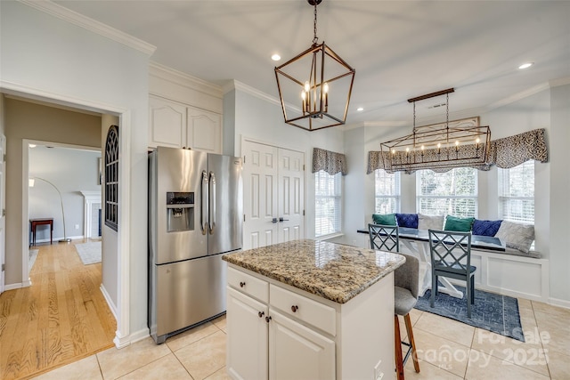 kitchen with hanging light fixtures, stainless steel refrigerator with ice dispenser, crown molding, a kitchen island, and white cabinetry