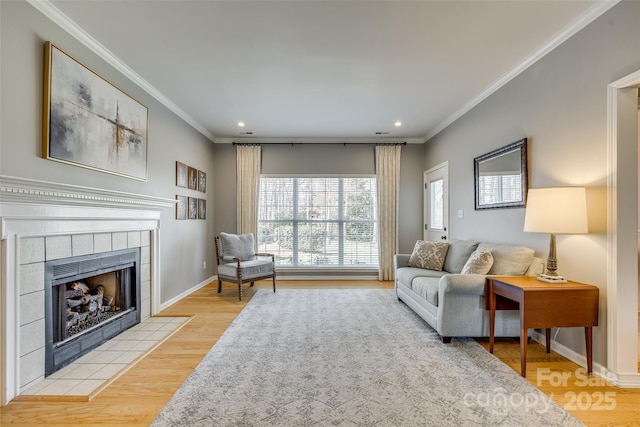 living room featuring a tiled fireplace, crown molding, and light hardwood / wood-style floors