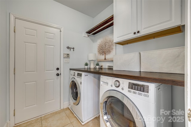 washroom featuring light tile patterned flooring, separate washer and dryer, and cabinets