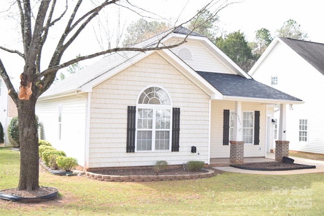 view of front of home with a shingled roof and a front lawn