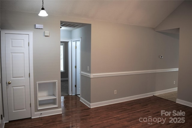 interior space featuring lofted ceiling, visible vents, baseboards, and wood finished floors