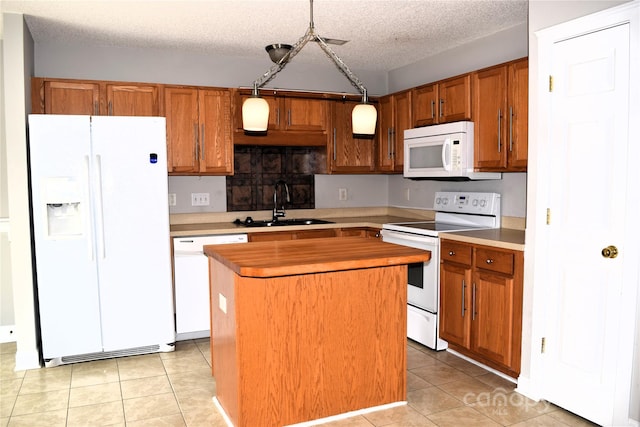 kitchen with white appliances, brown cabinets, a center island, a sink, and light tile patterned flooring