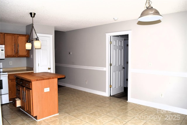 kitchen featuring white appliances, brown cabinetry, wood counters, decorative light fixtures, and a textured ceiling