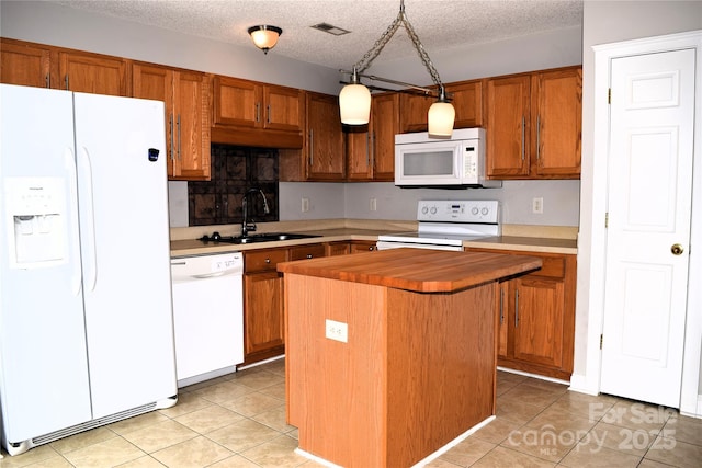 kitchen featuring white appliances, visible vents, a kitchen island, a textured ceiling, and a sink