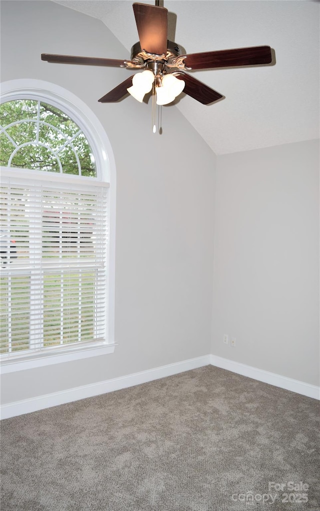 carpeted empty room featuring lofted ceiling, baseboards, and a ceiling fan