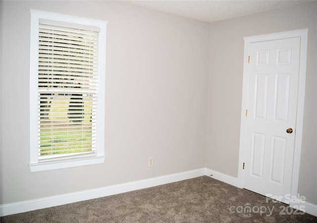 carpeted empty room featuring baseboards