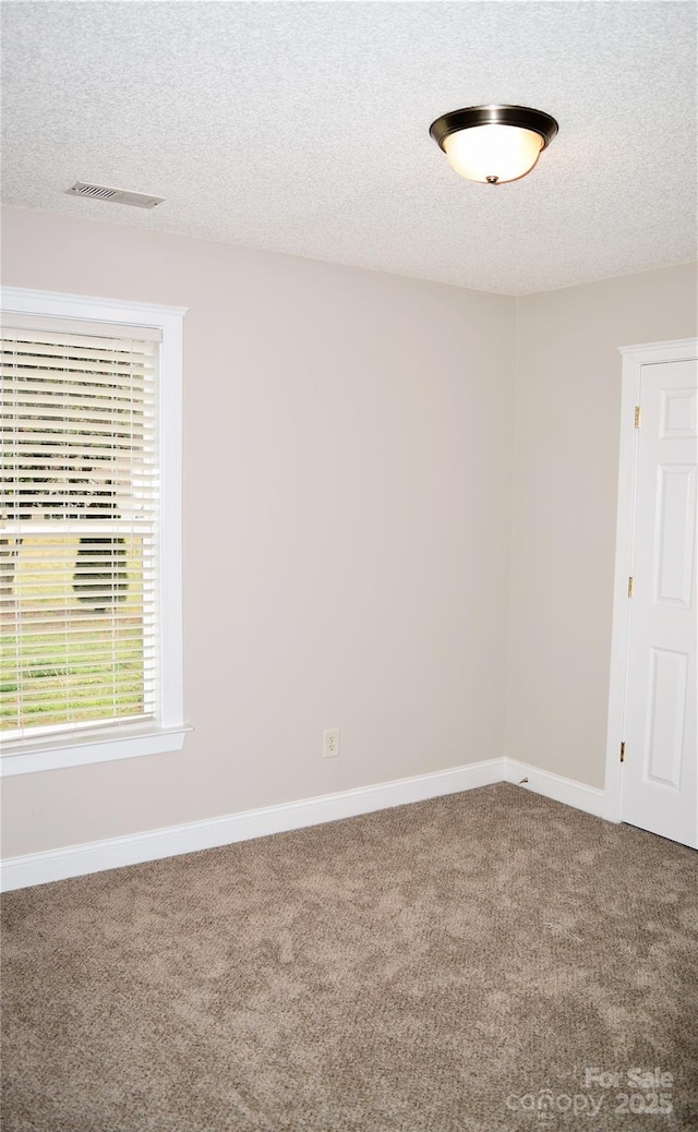 carpeted spare room featuring baseboards, visible vents, and a textured ceiling