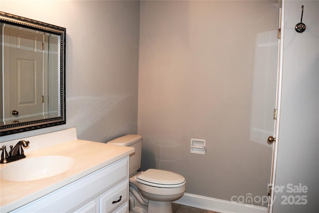 half bath featuring vanity, toilet, and baseboards