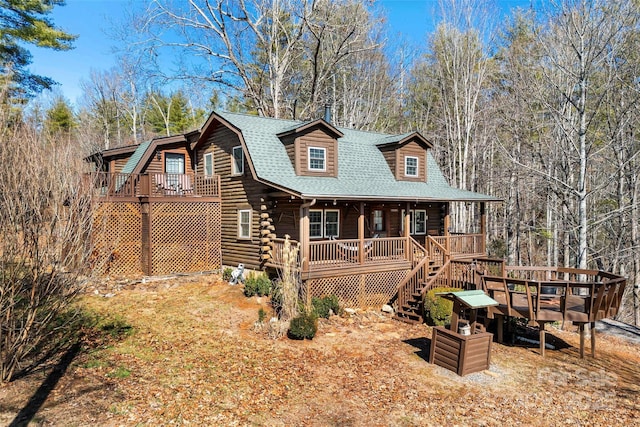 cabin featuring covered porch, roof with shingles, log siding, and a gambrel roof