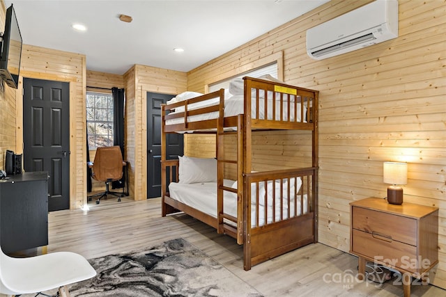 bedroom with recessed lighting, a wall mounted air conditioner, wood walls, and wood finished floors