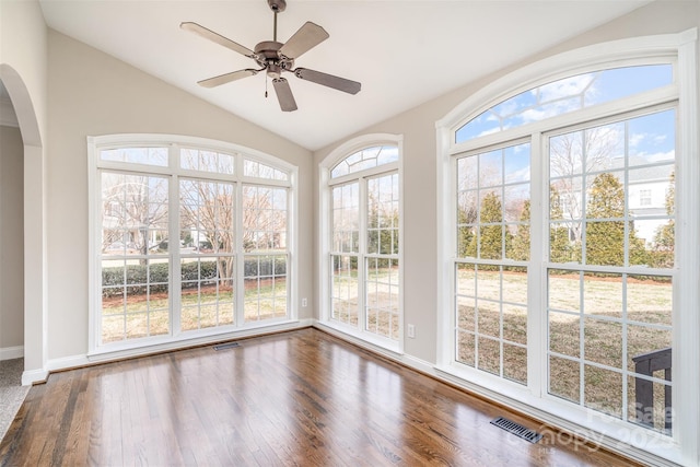 unfurnished sunroom featuring lofted ceiling, ceiling fan, visible vents, and arched walkways