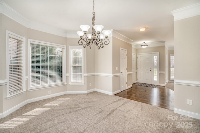 interior space featuring baseboards, dark carpet, a chandelier, and crown molding