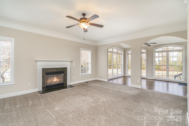 unfurnished living room with ceiling fan, carpet floors, a high end fireplace, and baseboards