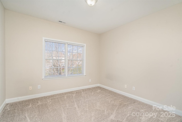 empty room with carpet flooring, visible vents, and baseboards