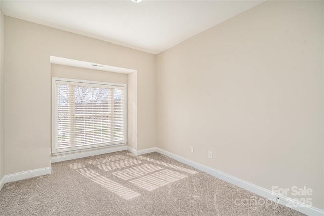 spare room featuring baseboards, visible vents, and light colored carpet