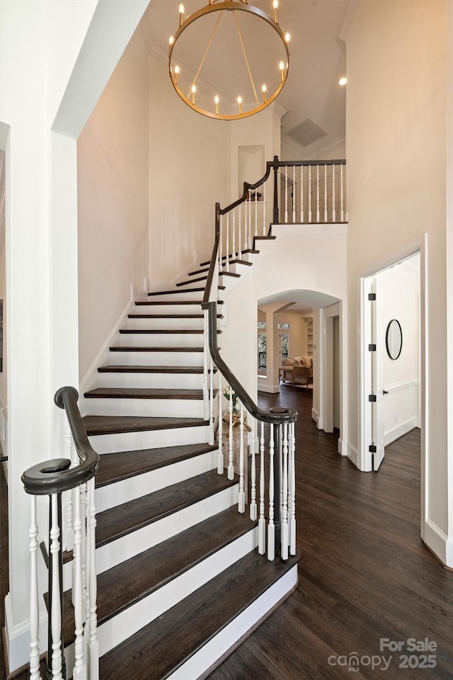 stairway featuring an inviting chandelier, hardwood / wood-style floors, and a high ceiling