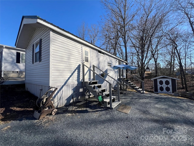 view of home's exterior with entry steps, a storage unit, and an outbuilding