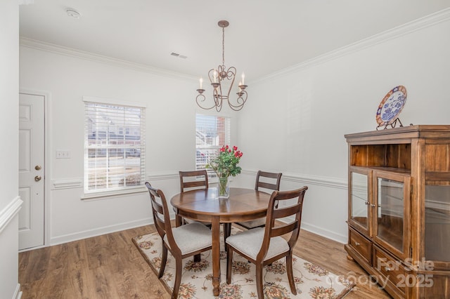 dining space with hardwood / wood-style floors, an inviting chandelier, and crown molding