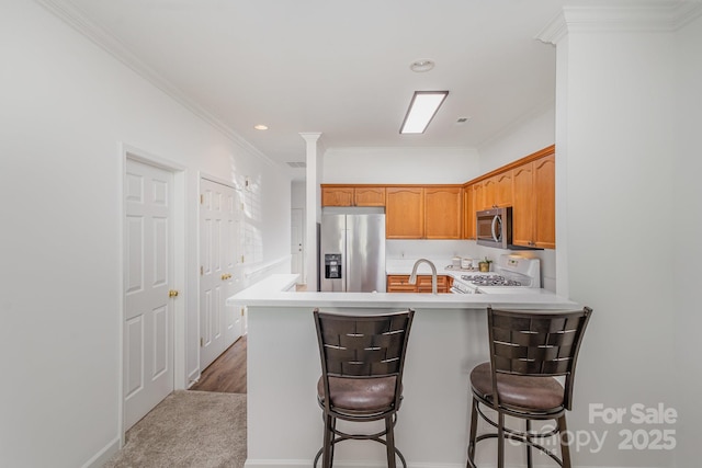 kitchen with a breakfast bar, carpet flooring, stainless steel appliances, kitchen peninsula, and ornamental molding