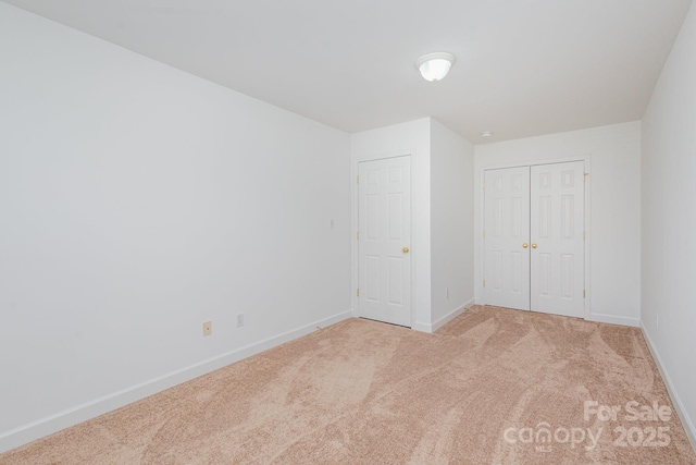 unfurnished bedroom with a closet and light colored carpet