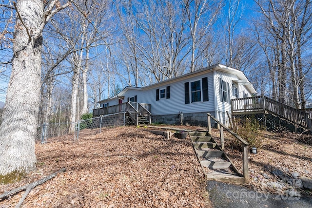 view of front of property with fence, a wooden deck, and stairs