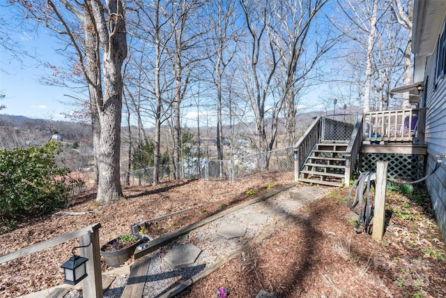 view of yard featuring stairway, fence, a deck, and dirt driveway