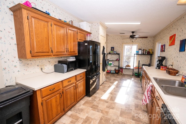 kitchen with black appliances, a sink, light countertops, and wallpapered walls