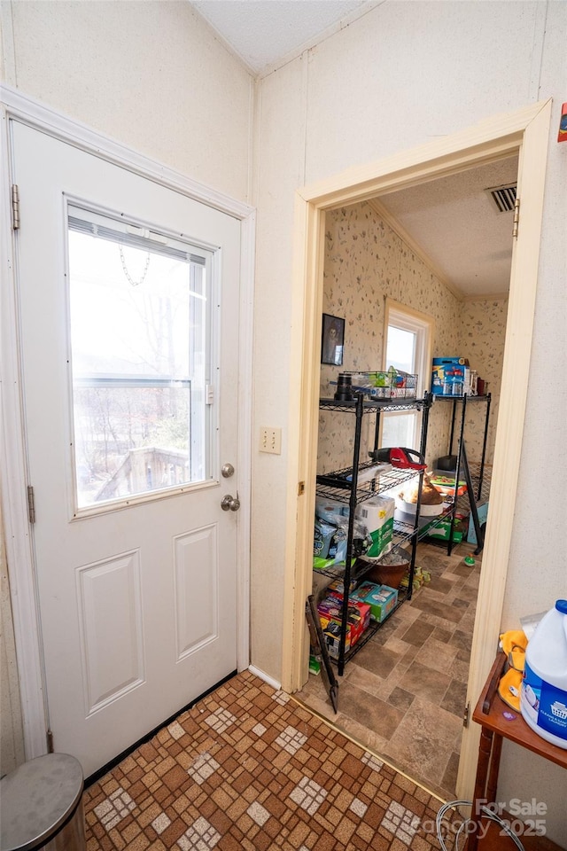 doorway to outside with brick floor, visible vents, and wallpapered walls