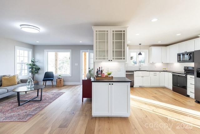 kitchen with dark countertops, light wood-style floors, appliances with stainless steel finishes, and decorative backsplash