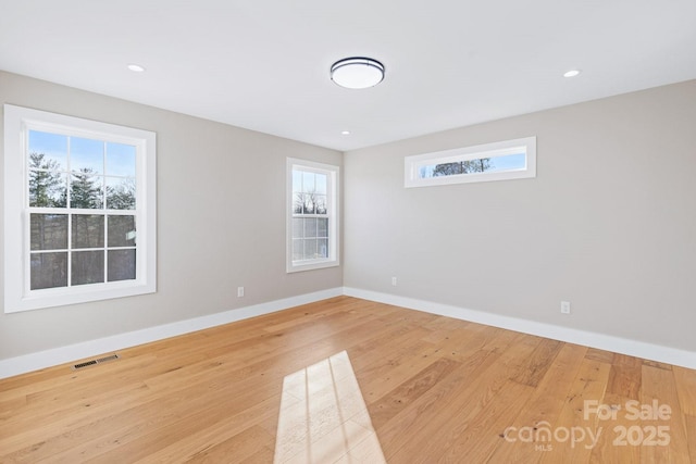 spare room with recessed lighting, wood finished floors, visible vents, and baseboards