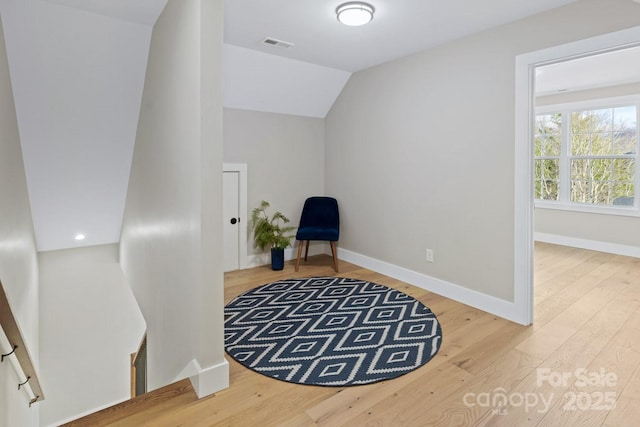 living area featuring vaulted ceiling, wood finished floors, visible vents, and baseboards