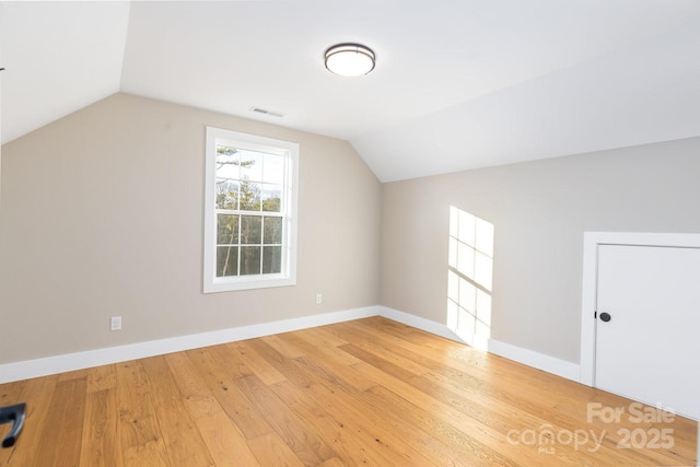 bonus room with baseboards, lofted ceiling, visible vents, and light wood-style floors