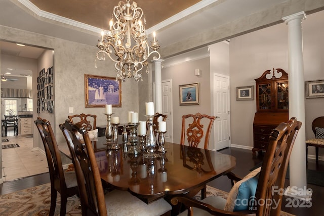 dining space featuring crown molding, wood-type flooring, a raised ceiling, and ornate columns