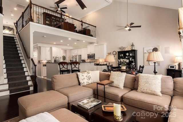 living room with a towering ceiling, dark wood-type flooring, and ceiling fan