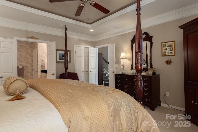 bedroom with carpet floors, ceiling fan, a tray ceiling, crown molding, and ensuite bath