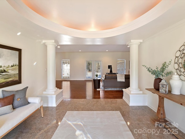 entryway featuring ornate columns and a raised ceiling