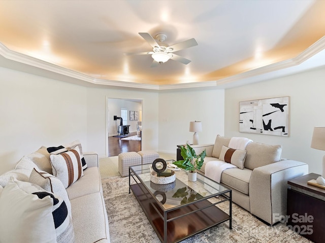 living room featuring crown molding, ceiling fan, and a raised ceiling